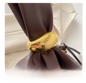 Detail of dark brown leather handbag featuring unique pebble-shaped gold metal hardware