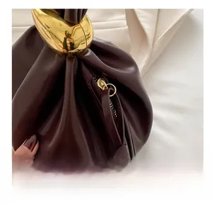 Macro shot of smooth zipper and liquid-style gold metal buckle on dark red leather bag