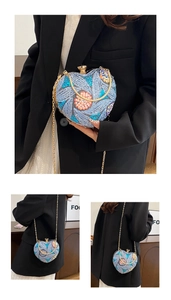 Detail of heart-shaped clutch with blue floral sequins, gold chain, and metal ball clasp