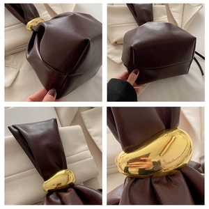 Detail view of brown leather bucket bag with artistic gold hardware and pleated texture