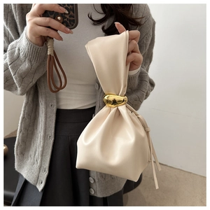 Detail of cream pleated bucket bag with gold pebble metal ring and soft leather texture