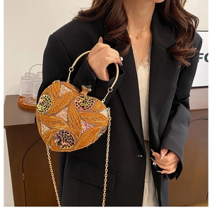 Detail of heart-shaped gold sequin evening bag with floral embroidery and metal handle