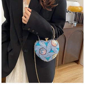 Macro detail of heart-shaped clutch with colorful sequins and golden ring handle