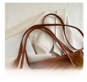 Detail of adjustable faux leather shoulder straps and golden buckle on plush tote bag