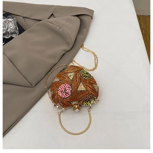 Detail of heart-shaped evening bag featuring gold floral embroidery and sequins with chain