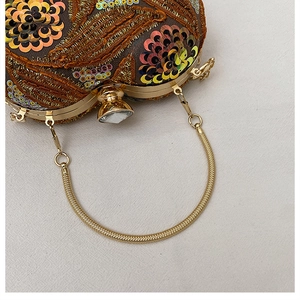Detail of evening clutch with gold embroidery, sequins, and crystal clasp closure