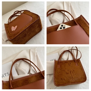 Detail of plush brown tote with pink butterfly embroidery and functional side phone pocket