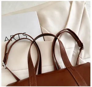 Detail of dark brown faux leather tote with reinforced handles and silver metal buckle