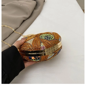 Close-up of evening clutch with gold leaf embroidery, floral sequins, and metal chain
