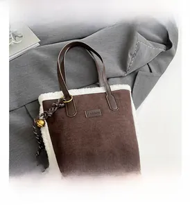 Détail du sac seau en daim marron avec bordure en fausse fourrure blanche et grelot doré