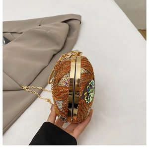 Close-up of orange sequin embroidery on an evening clutch with gold chain strap