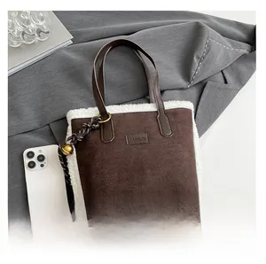 Détail du sac seau marron en suédine avec garniture en polaire blanche et breloque dorée