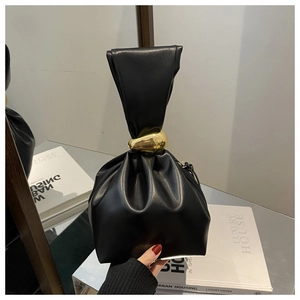 Détail d'un sac à main noir en cuir plissé avec un ornement en métal doré sur la poignée