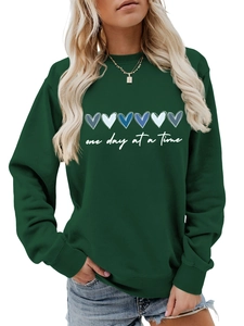 Dettaglio felpa verde scuro con cuori blu sfumati e scritta One Day at a Time