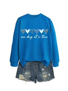 Dettaglio della felpa blu con grafica a cuore e pantaloncini in denim effetto usato