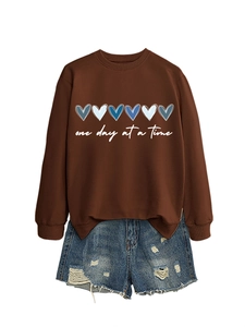 Felpa marrone con cuori blu e pantaloncini di jeans strappati in posa piatta