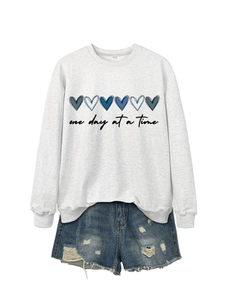 Dettaglio della felpa grigia con scritta e pantaloncini di jeans blu con strappi moda