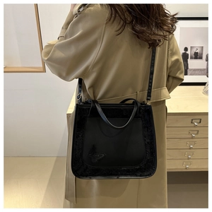 Detail of black faux fur patchwork tote bag with butterfly embroidery worn on shoulder