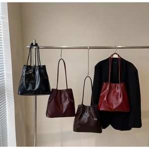 Detail of four retro glossy patent leather tote bags in black, burgundy, coffee, and red