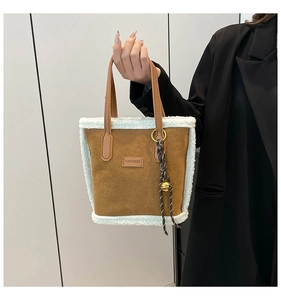 Gros plan sur un sac seau en daim marron avec bordure en fourrure et breloque clochette