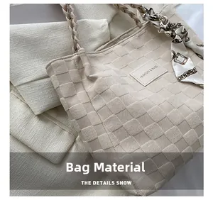 Detail of beige woven canvas tote with silk scarf handle and brand logo patch