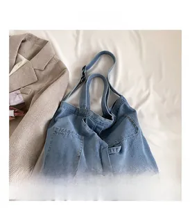 Close-up of light blue denim tote bag with two front pockets and wide shoulder strap