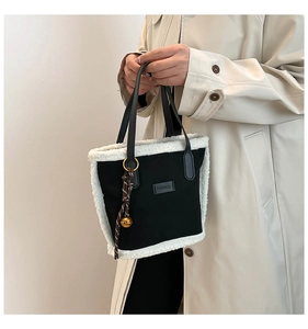 Dettaglio borsa a secchiello nera con bordo in pile bianco e ciondolo alla moda