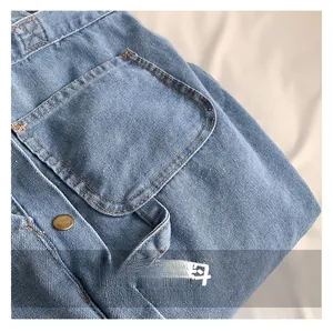 Detailed macro shot of heavy denim fabric with orange stitching and vintage bronze button