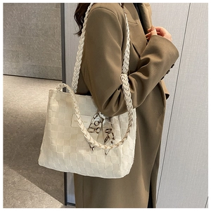 Close-up of white woven tote bag featuring a chunky braided strap and decorative floral scarf