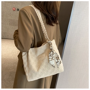 Detail of canvas tote bag featuring woven texture, twisted strap, and decorative silk scarf
