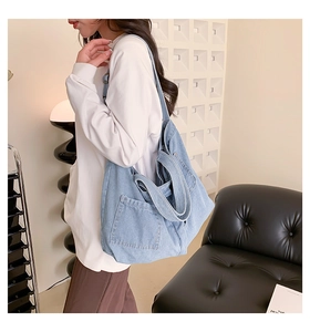 Detail of light blue denim tote bag featuring spacious side pockets and wide straps