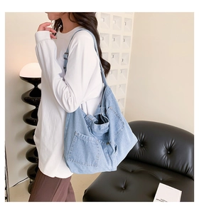 Detail view of light blue denim tote bag with functional front pocket and metal snap