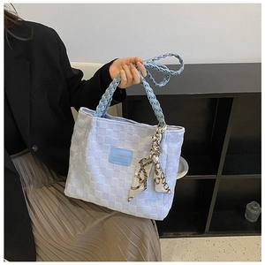 Detail of light blue woven tote bag featuring braided handle and silk scarf accessory
