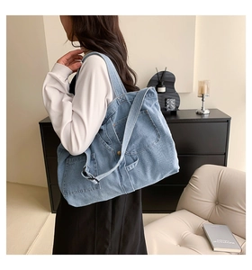 Side view of large denim tote bag with pockets and long strap on model