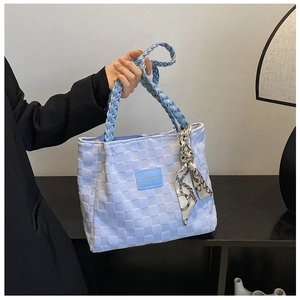 Detail of light blue woven tote bag with silk scarf handle and golden fashion logo