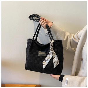 Detail of black woven tote bag with silk scarf accessory and fashion leather label