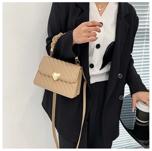 Détail d'un mini sac beige matelassé avec fermoir cœur doré et poignée plissée