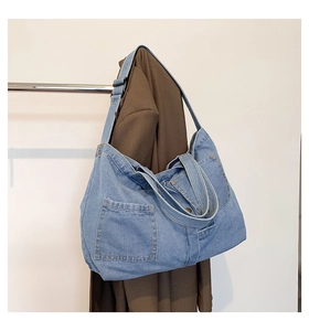 Close-up of blue denim tote bag featuring white contrast stitching and adjustable strap
