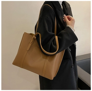 Detail van een bruine leren shopper met verticale stiksels voor de herfst