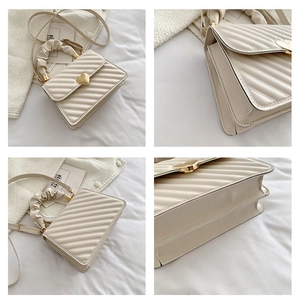 Details der cremefarbenen Plissee-Handtasche mit goldenem Herzschloss und Wolkengriff