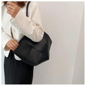 Detail of black wide-weave tote bag showing texture and intrecciato style craftsmanship