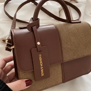 Detailweergave van de bruine patchwork handtas met textuurstof en leren logo-label