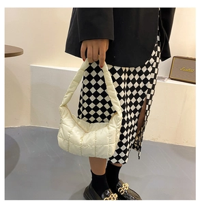 Chic white quilted hobo bag with moon shape worn by model in fashionable urban outfit