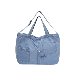 Blue denim tote bag with jacket-style pockets and adjustable shoulder strap on white base