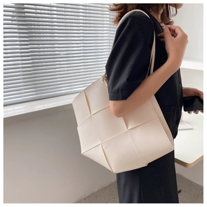Detailed view of cream woven tote bag with wide strap texture and side fold structure