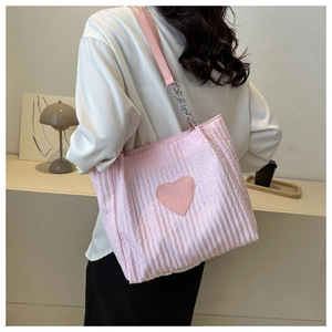 Detalle de bolso tote rosa acolchado con parche de corazón y correa de cadena en modelo