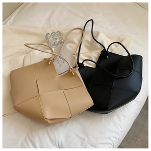 Detailed view of woven leather tote bags with minimalist golden hardware and strap