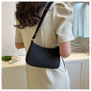 Detail der schwarzen gesteppten Filz-Unterarmtasche am Modell in eleganter Lifestyle-Umgebung