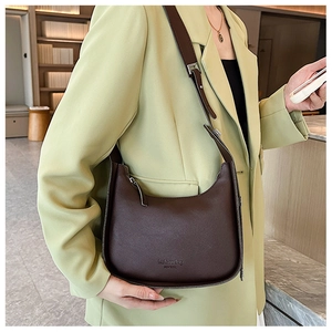 Deep brown crescent shoulder bag with New York lettering on a light green blazer