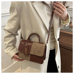 Detail van het contrast tussen bruin leer en camel tweed textuur op de schoudertas